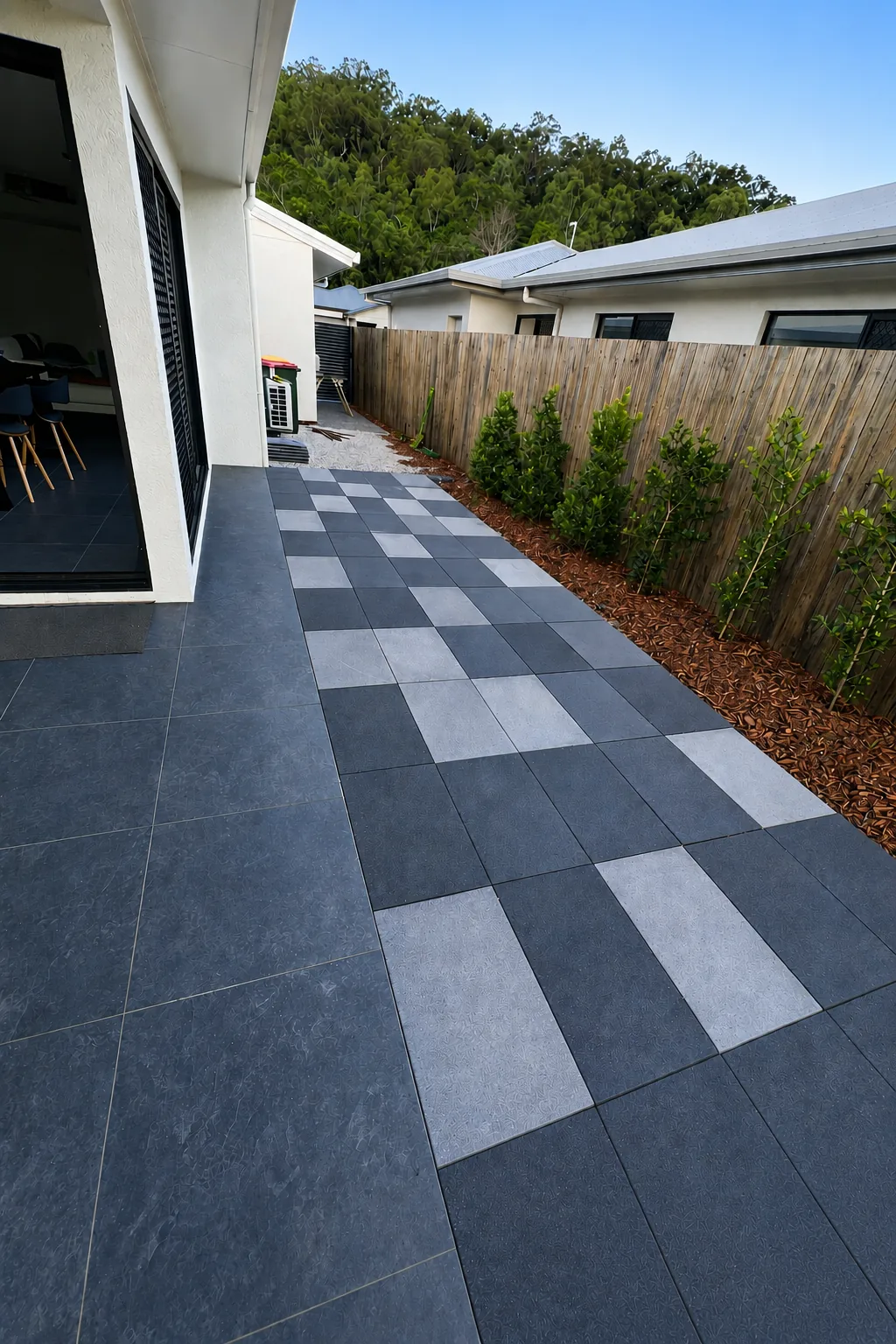 Extended paved courtyard and screening plants creating an outdoor living area at a Cairns home