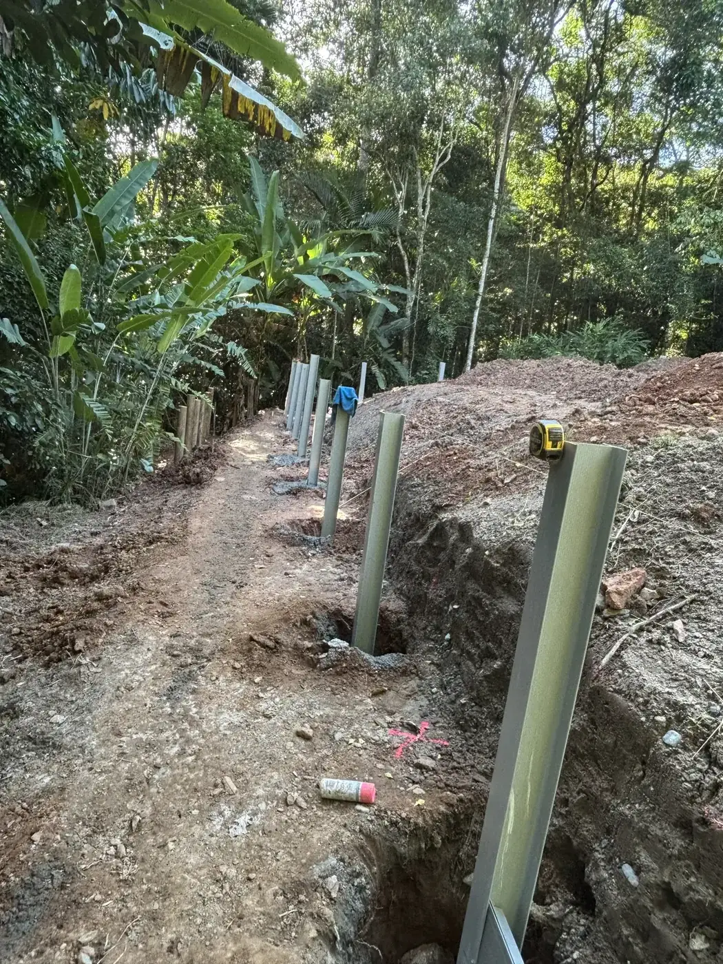 Super Sleeper retaining wall posts being installed on sloping ground in Cairns
